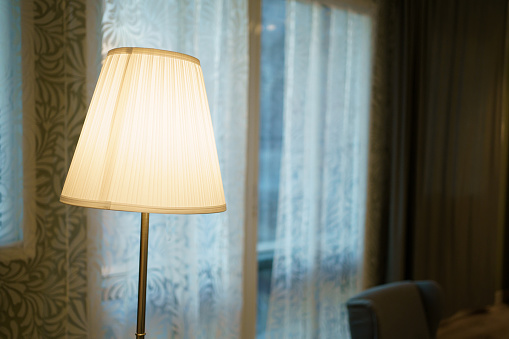 Close up shot with copyspace of classic floor lamp left beside the window.