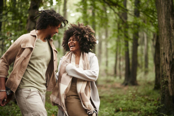Cheerful black couple having fun while running in nature.