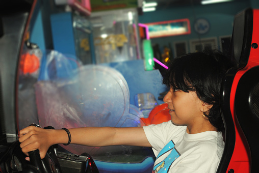 Asian teenage girl is playing in amusement arcade.