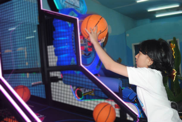 Girl is playing basketball in amusement arcade.