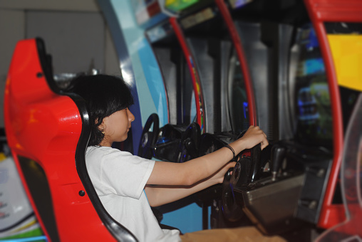 Asian teenage girl is playing in amusement arcade.
