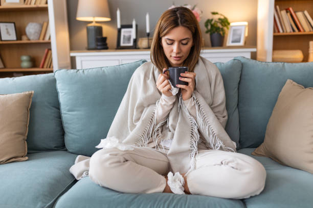 istock Sickness, seasonal virus problem concept. Woman being sick having flu drinking tea on sofa. Sick woman lying in bed with high fever. Cold flu and migraine. 2129334113