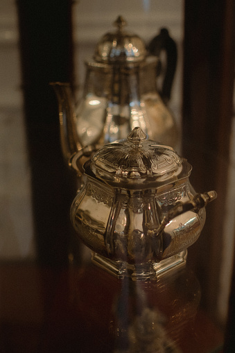 Two antique silver teapots displayed on a museum table