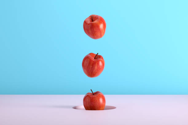 istock Red apples falling from a hole on blue and pink colored background. 2129336785
