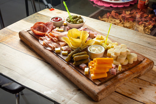 Assortment of meats, cheeses, and pickles on a wooden board