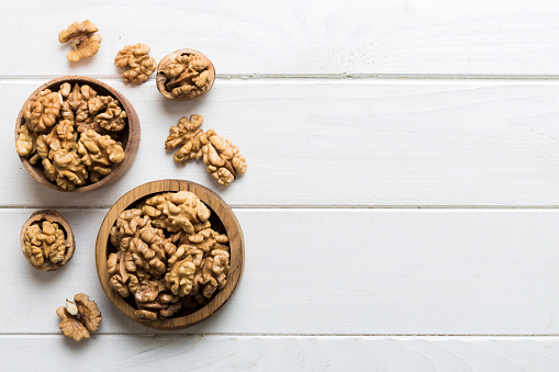 Fresh healthy walnuts in bowl on colored table background. Top view Healthy eating bertholletia concept. Super foods.