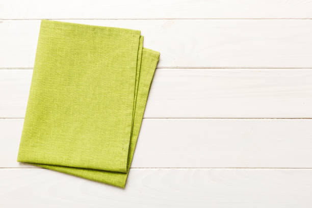 istock top view with green kitchen napkin isolated on table background. Folded cloth for mockup with copy space, Flat lay. Minimal style 2129381757