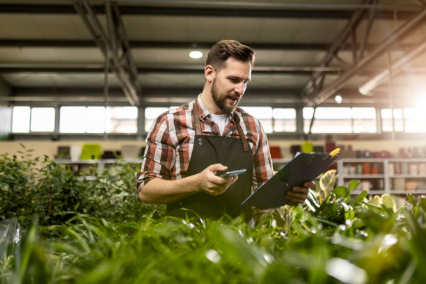 istock Florist Worker Oversees Operations with Clipboard and Phone 2129388767
