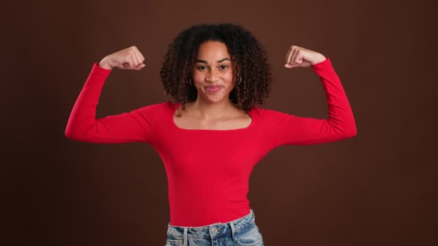 Woman gesturing strength flexing bicep and smiling at camera