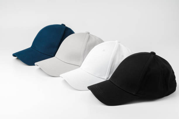 istock Four Baseball Caps in Black, White, Grey, and Blue Arranged on a Plain Background 2129438253