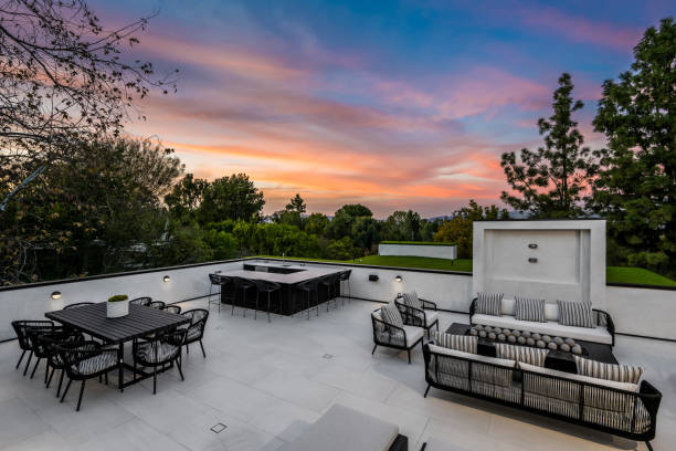 istock Outdoor patio with an illuminated firepit, chairs, and tables at sunset. 2129447035