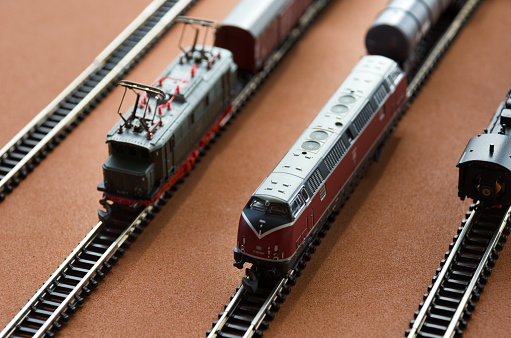Toy passenger train and railroad with selective focus effect. Model of a locomotive on a dark background. Railway and trains.