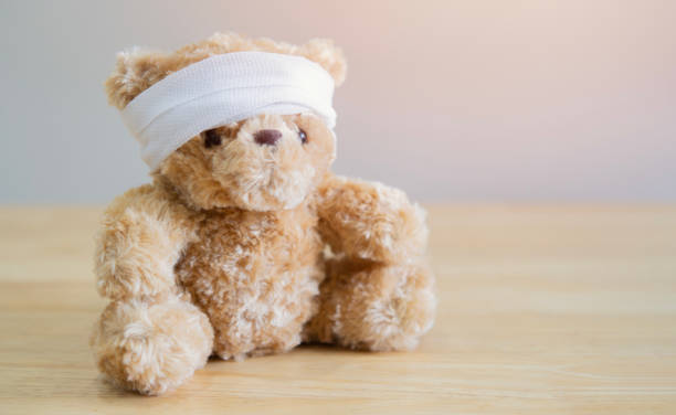 istock The child is hurt. Teddy bear with bandage sit on wooden table with space for text. 2129477350