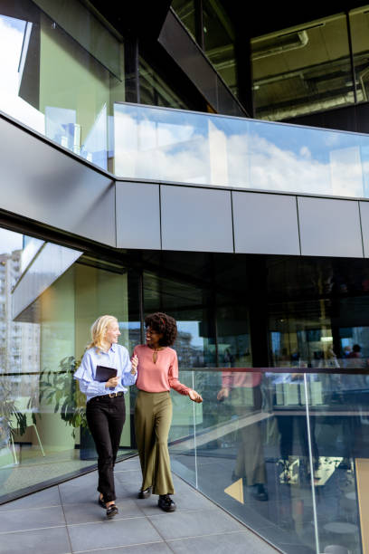 istock Two Professional Women Sharing a Joyful Conversation at a Modern Office Building 2129478402