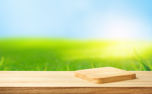 Selective focus.wood counter top with cutting board on blur greeny lawn grass background
