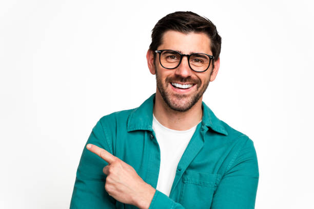 istock Smiling man pointing to the side on neutral background 2129490917