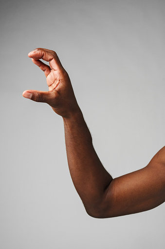 African Mans Arm Revealing Muscular Strength on gray background close up