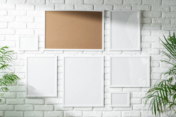 istock Varied Sized Photo Frames Displayed on a White Brick Wall 2129500022