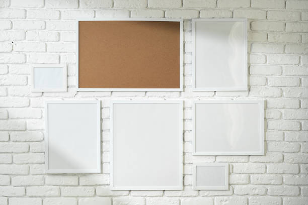 istock Varied Sized Photo Frames Displayed on a White Brick Wall 2129500026