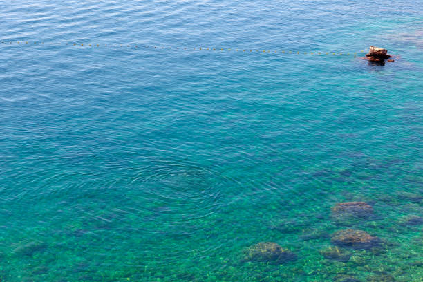 Turquoise sea water background. Transparent water with rocks on the bottom