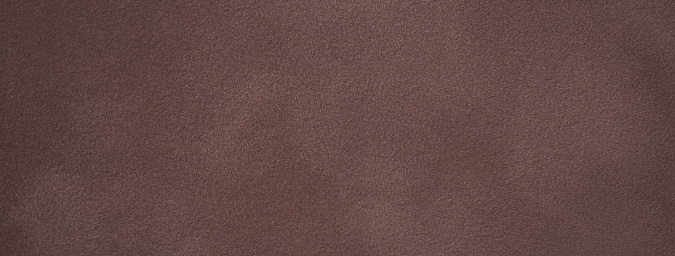 Dark brown matte background of suede fabric, closeup. Velvet texture of umber seamless textile, macro. Structure of felt canvas backdrop.