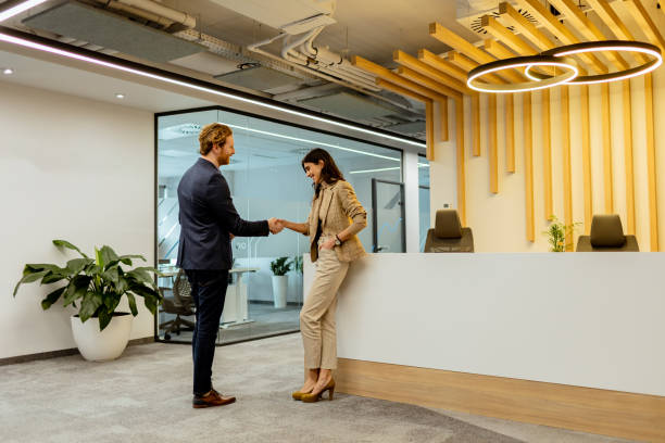 istock Warm Handshake Between Colleagues In Modern Office Lobby Under Ambient Lighting 2129516631