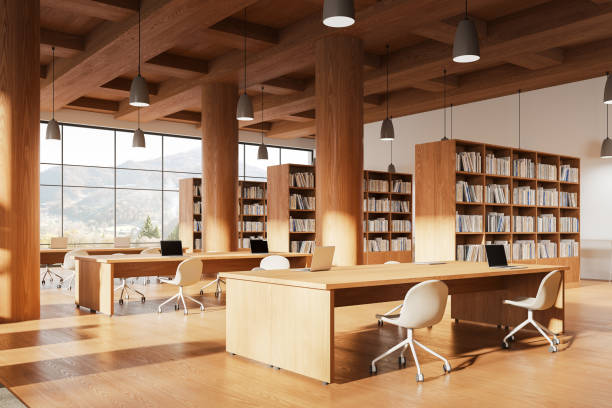 istock Modern library interior with workplace and laptop, bookshelf and window 2129521548
