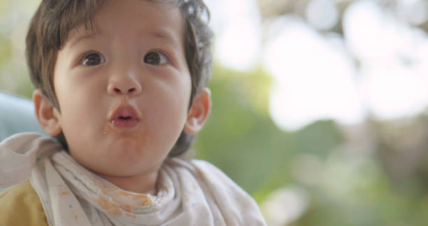 Asian boy eating food at home. Kid learning  using hand.