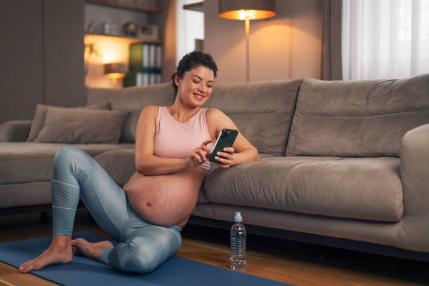 istock A happy pregnant woman scrolling through her phone while taking a break from her home workout 2129532336