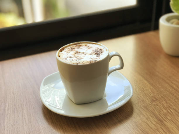 istock Cappuccino in a white cup on a wooden table. 2129542963