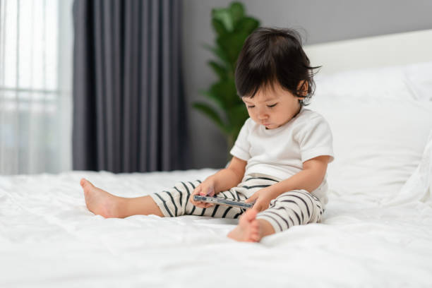 istock toddler baby using and watching smartphone on bed 2129561339