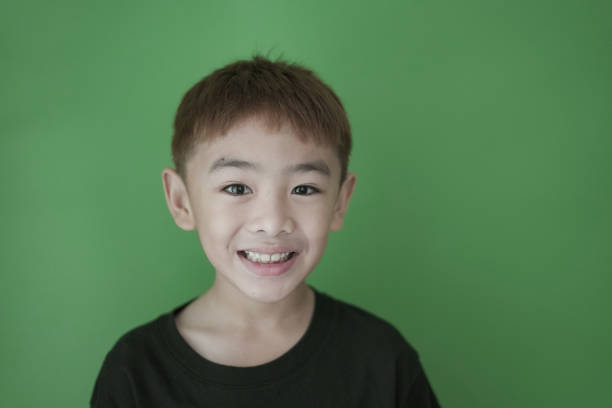 Close-up boy smiling on green wall
