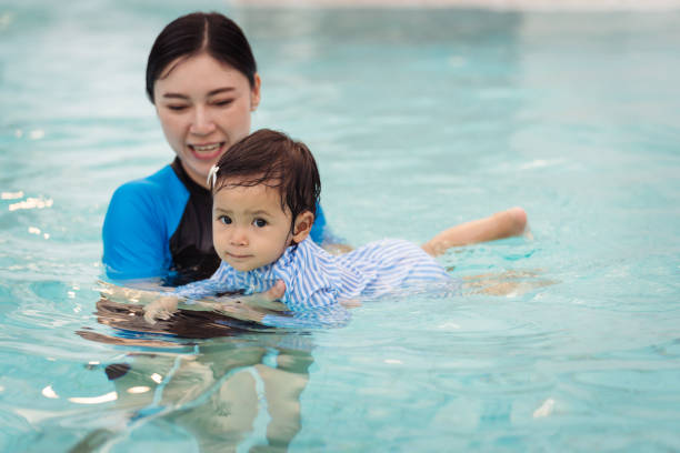 mother teaching her daughter swimming in pool