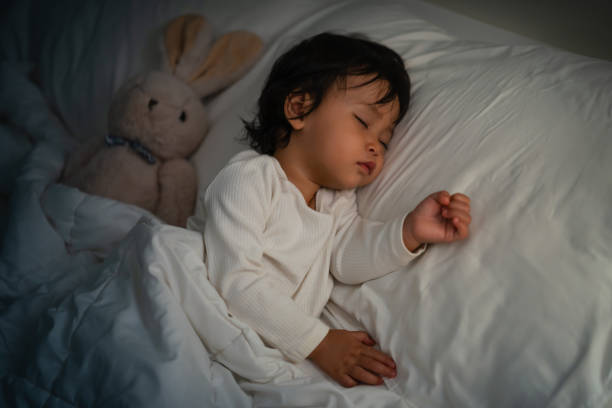 istock toddler baby sleeping with teddy bear on bed at night 2129578801