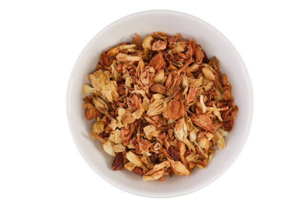 Pile of dried jasmine blossoms (Jasminum officinale) in a white bowl. Close-up, table top view, isolated on white background.