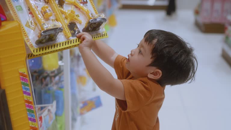 Happy Asian boy choose the toys that are on the shelf.