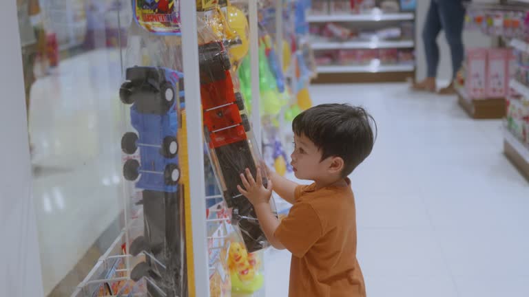 Happy Asian boy choose the toys that are on the shelf.