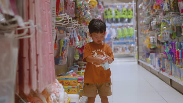Happy Asian boy choose the toys that are on the shelf.