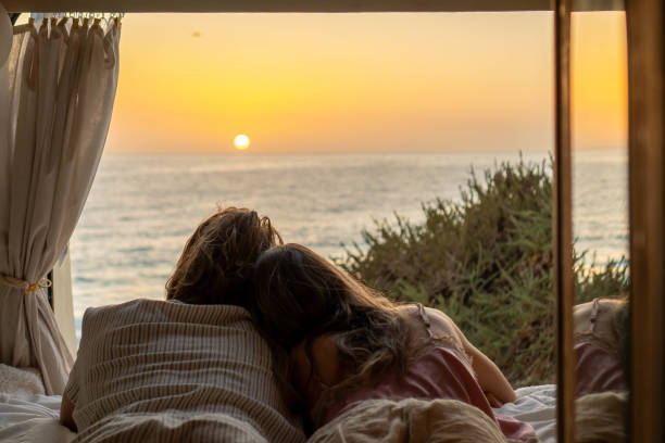 istock Couple Embracing Sunrise From Van by the Sea 2129601778