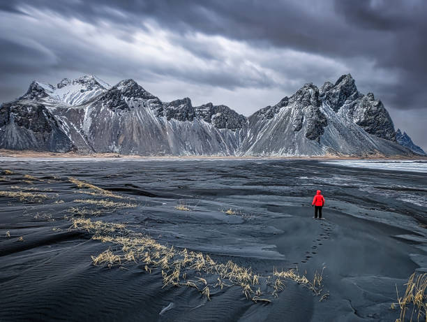 istock Man exploring Stokksnes with Vestrahorn mountain in the background 2129628752
