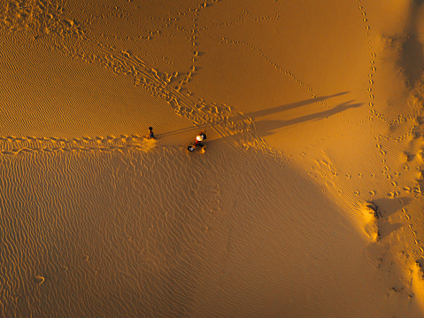 Aerial view of a peasant woman carries a bamboo frame on the shoulder across sand dunes in Ninh Thuan province, Vietnam. It is one of the most beautiful places in Vietnam for travel and photography