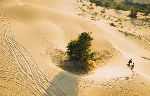 Aerial view of a peasant woman carries a bamboo frame on the shoulder across sand dunes in Ninh Thuan province, Vietnam. It is one of the most beautiful places in Vietnam for travel and photography