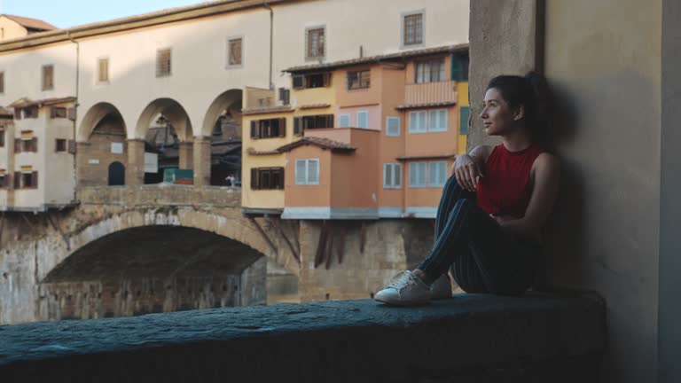 Pretty asian woman having rest on the Vecchio bridge in Florence . Beautiful young girl enjoying silence and view of the Arno river. Concept of peace, calmness and beauty.