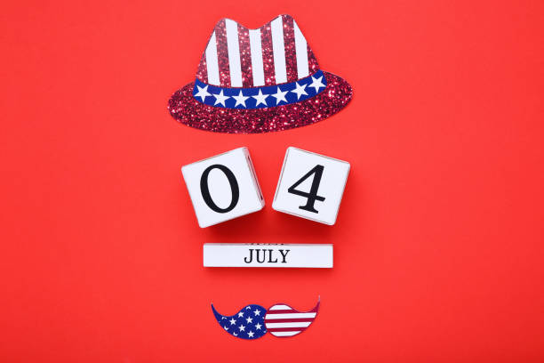istock Independence Day concept. Cube calendar with paper hat and mustache on red background 2129649898