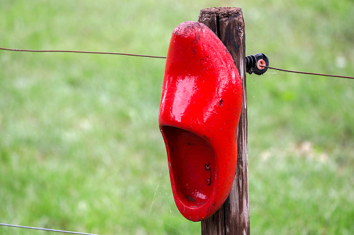 red-painted wooden clog nailed to a fence as an ornament in the Netherlands
