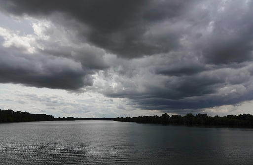 A formation of dark rain clouds above a reservoir in East Anglia, UK.
