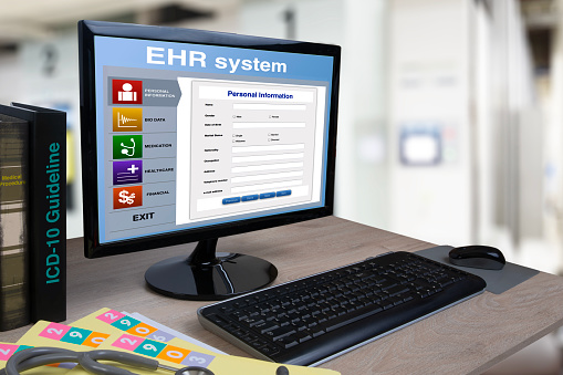 Desktop computer on working desk in hospital office that showing electronic health record system on screen.