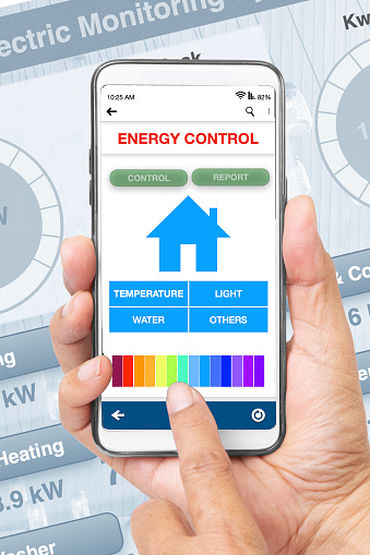 Hand holding smartphone showing energy control application on screen.