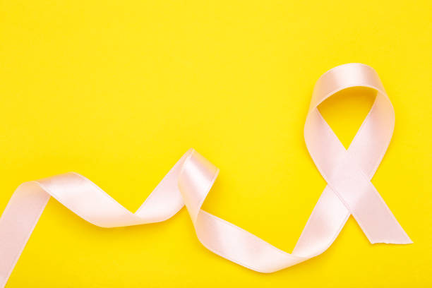 istock Cancer concept. Pink ribbon on yellow background 2129683742