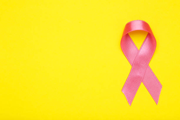 istock Cancer concept. Pink ribbon on yellow background 2129695526